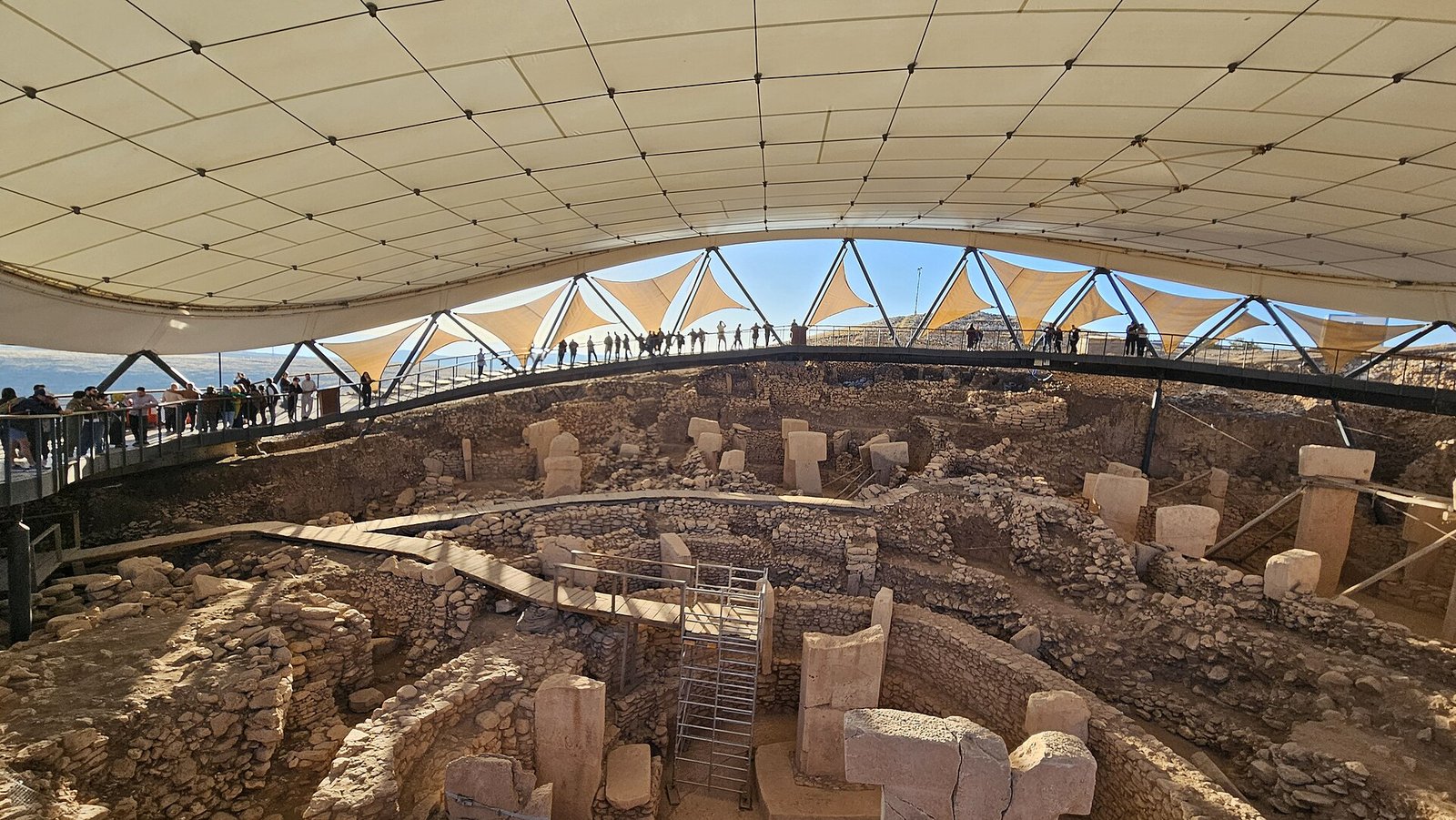Göbeklitepe kazı alanını örten koruma çatısı ve yürüme yolundaki ziyaretçiler
