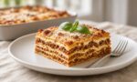 Katmanları görünen bir dilim lazanya, ragù sosu ve beşamelle modern beyaz tabakta