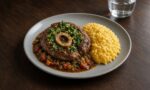 Modern, sade gri tabakta gremolata serpilmiş Milano usulü dana incik ve yanında sarı renkli safranlı risotto