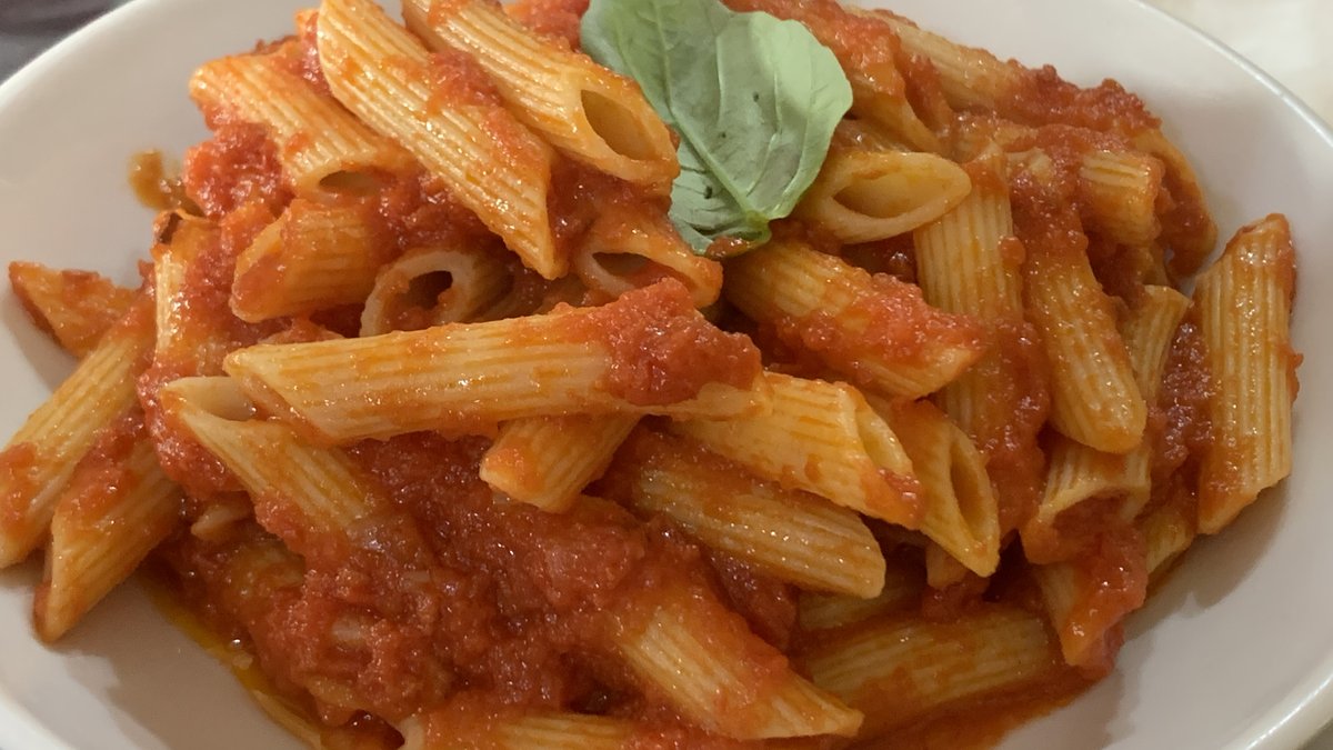 Penne arrabbiata tarifi: fesleğen yaprağıyla süslenmiş domates soslu penne, beyaz tabakta