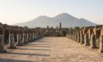 Pompei’de Forum meydanının sütun kalıntıları ve arkada yükselen Vezüv Yanardağı, temsili görsel